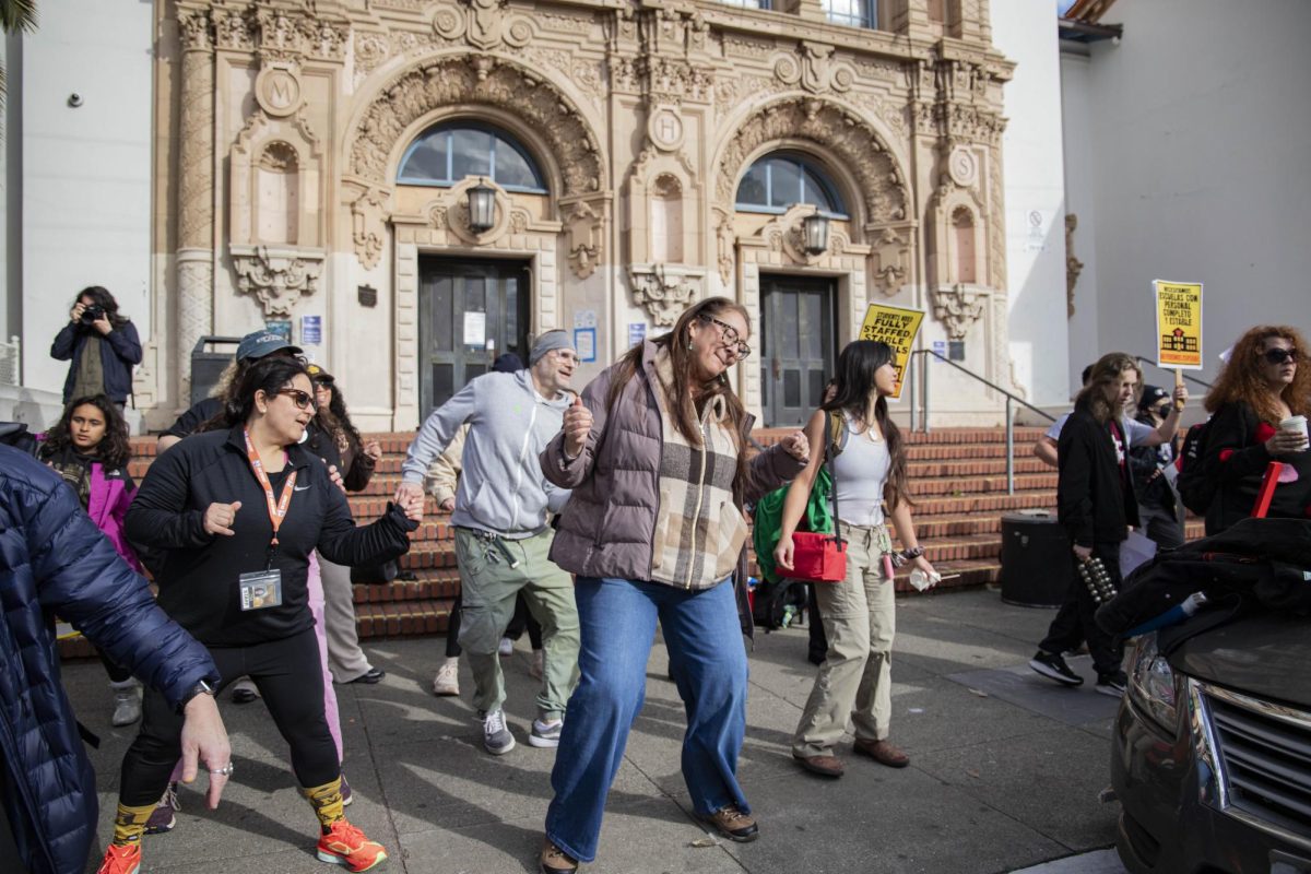 Ms. Rodríguez (in the center), with a half-up hairstyle and blue jeans, dancing.
